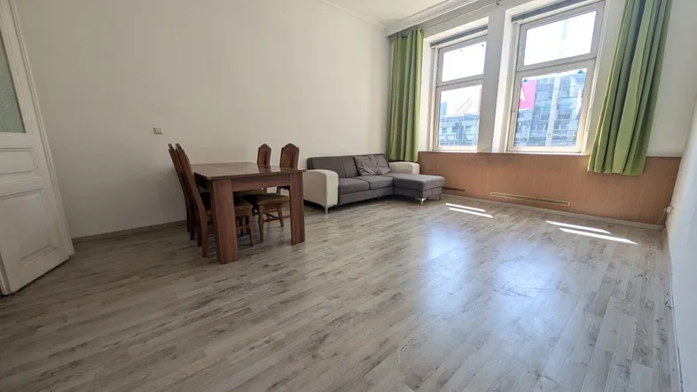 Helles Wohn- und Esszimmer mit Laminatboden, großzügigen Fenstern und einem Esstisch.