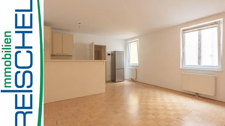 Helles Wohnzimmer mit Parkettboden und integrierter Küchenzeile, ideal für offenes Wohnen.