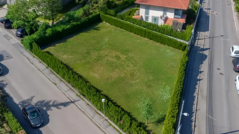 Luftaufnahme eines dreieckigen Grundstücks mit gepflegter Hecke und angrenzender Straße.