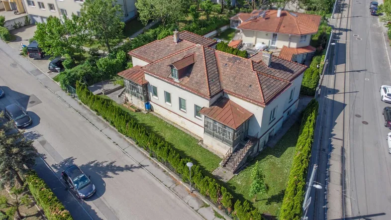 Luftaufnahme eines charmanten Hauses mit traditionellem Ziegeldach und gepflegtem Gartenbereich.