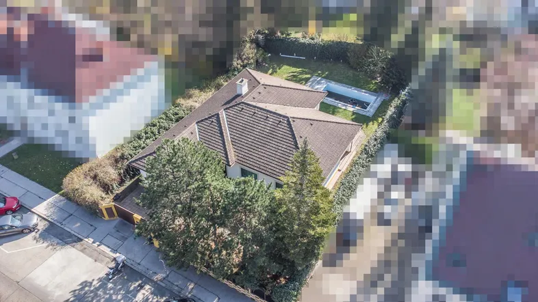 Luftaufnahme eines Hauses mit Ziegeldach, großem Garten und Swimmingpool in einer Wohngegend.