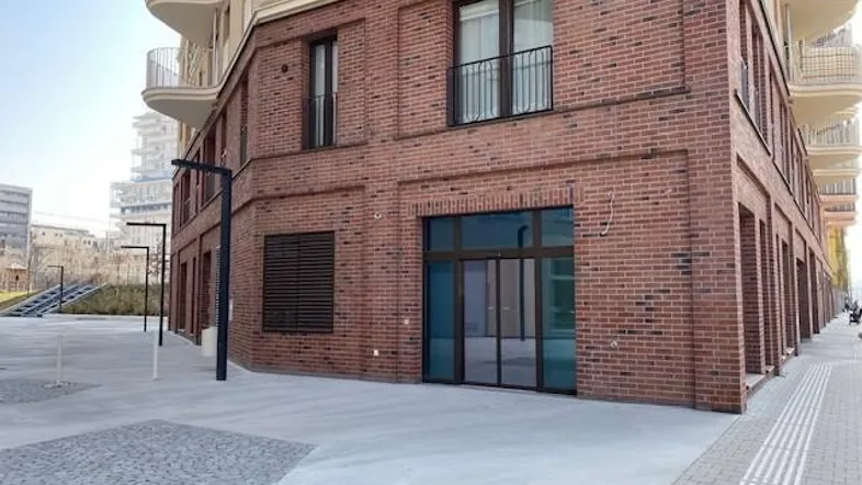 Modernes Gebäude mit Ziegelfassade und geschwungenen Balkonen in einer städtischen Umgebung.