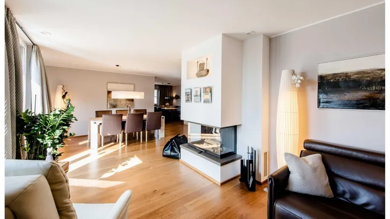 Helles, offenes Wohn- und Esszimmer mit Holzboden, modernem Kamin und bequemen Sitzgelegenheiten.