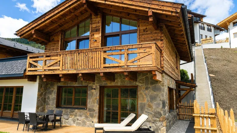 Charmantes Holzchalet mit Steinfassade, großer Terrasse und Balkon in alpiner Umgebung.