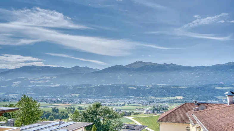 Panoramablick auf die umliegende Berglandschaft mit Solaranlagen auf den Dächern.