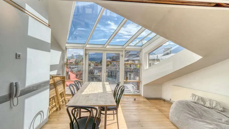 Heller Essbereich mit Holztisch, Stühlen und großzügiger Glasfront, die auf eine Terrasse führt.