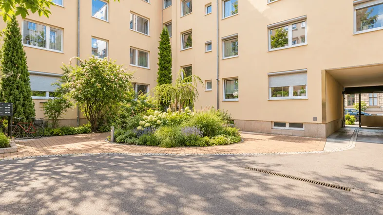 Gepflegter Innenhof mit Grünflächen und Bäumen, umgeben von der Wohnanlage.