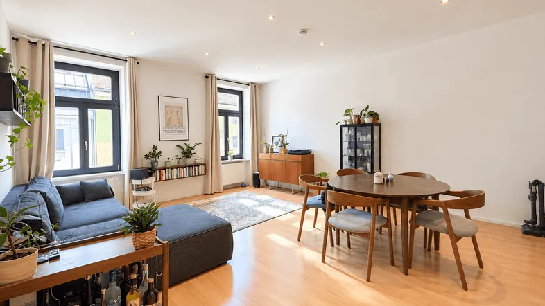Helles und geräumiges Wohn-Esszimmer mit Holzboden, bequemer Couch und modernem Esstisch.