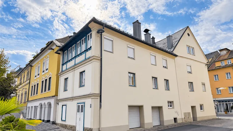 Fassade eines historischen Gebäudes mit gelben und beigen Abschnitten unter blauem Himmel.