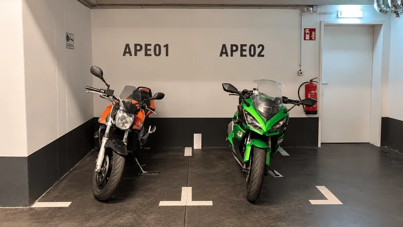 Tiefgarage mit zwei Motorradstellplätzen, Brandschutzvorrichtungen und klarer Beschilderung.