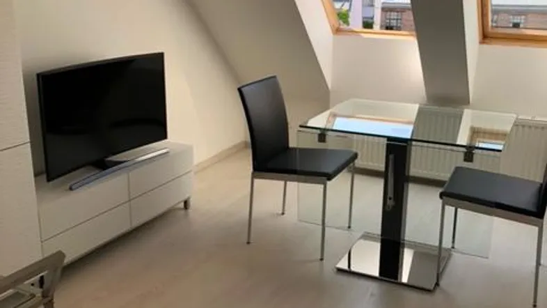Helles Wohnzimmer im Dachgeschoss mit Schrägdach, Dachfenstern und modernem Esstisch.
