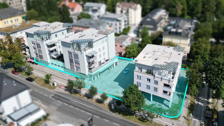 Luftaufnahme des modernen Gebäudekomplexes mit markierter Grundstücksgrenze und umliegender Bebauung.