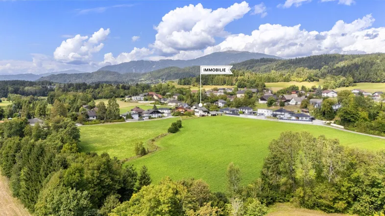Luftaufnahme der Immobilie in einer ländlichen Umgebung mit grünen Feldern und Bergen im Hintergrund.