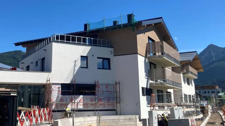 Neubauprojekt in Bauphase mit moderner Architektur und Bergblick im Hintergrund.