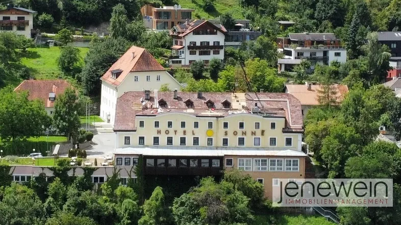 Luftaufnahme des Hotels Sonne in einer grünen Berglandschaft mit umliegenden Gebäuden und weitem Blick.