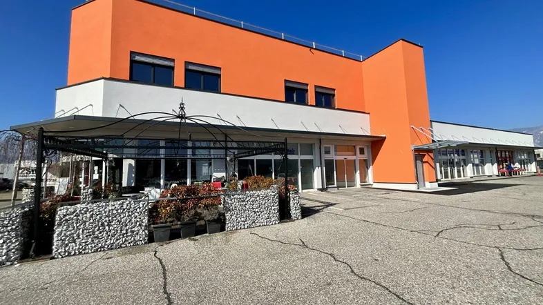Modernes Geschäftsgebäude mit auffälliger orangefarbener Fassade und großem Parkplatzbereich davor.