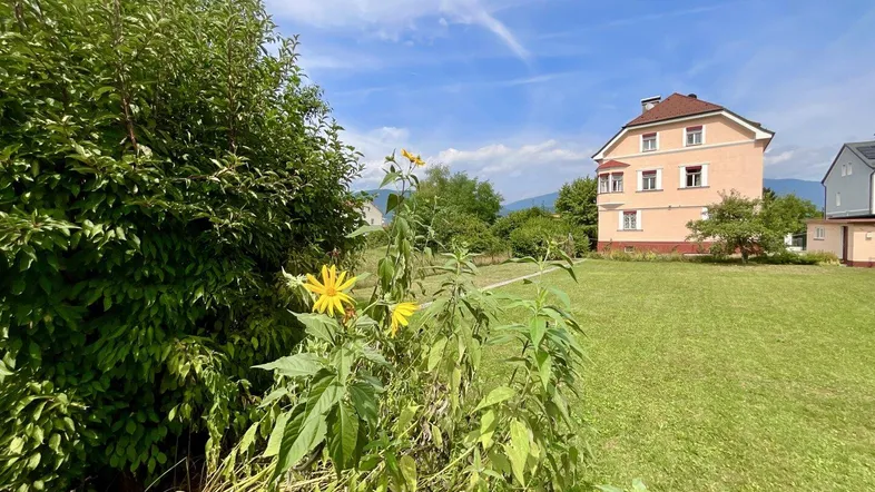 Weitläufiger Garten mit grüner Rasenfläche und Blick auf die umliegende Landschaft.