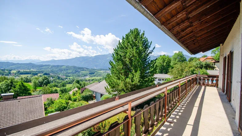 Geräumiger Balkon mit traditionellem Holzgeländer und weitem Blick auf die umliegende Berglandschaft.