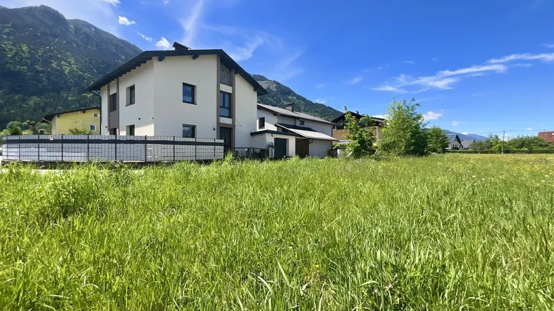 Hausfassade mit weitem Blick auf die umliegende Berglandschaft und grüne Wiesen.