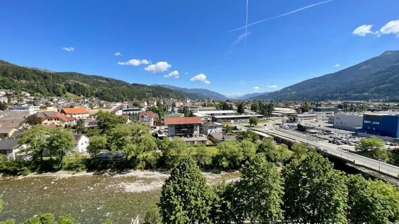 Panoramablick über die Stadt mit Fluss, Bergen und umliegender Landschaft unter blauem Himmel.