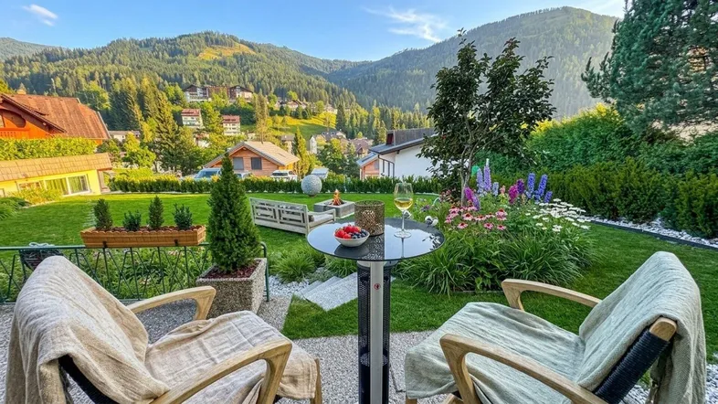 Gemütlicher Gartenbereich mit Sitzgelegenheiten, Feuerstelle und weitem Blick auf die umliegenden Berge.