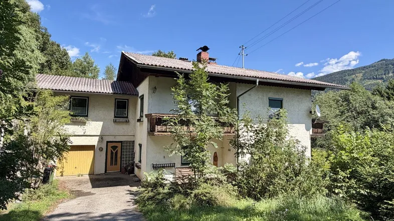 Traditionelles Einfamilienhaus mit Satteldach, Garage und Balkonen in ländlicher Umgebung.