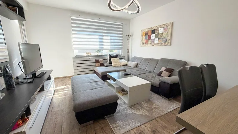 Helles Wohnzimmer mit modernem Sofa, Holzboden und dekorativer Deckenleuchte, einladend gestaltet.
