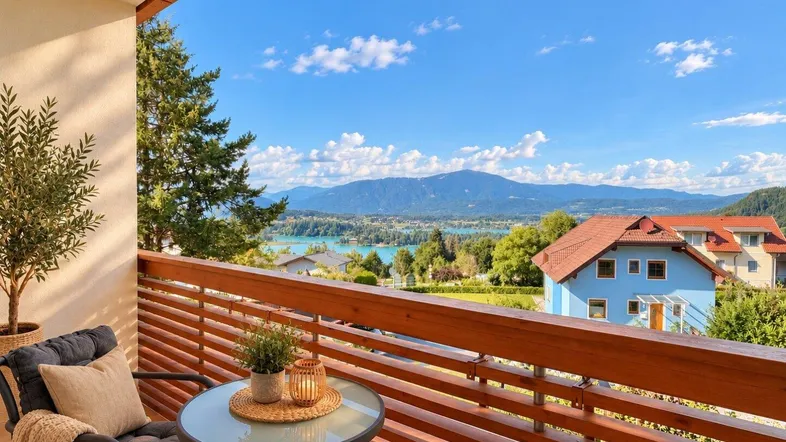 Möblierter Balkon mit Holzboden und atemberaubendem Blick auf den See und die Berge.