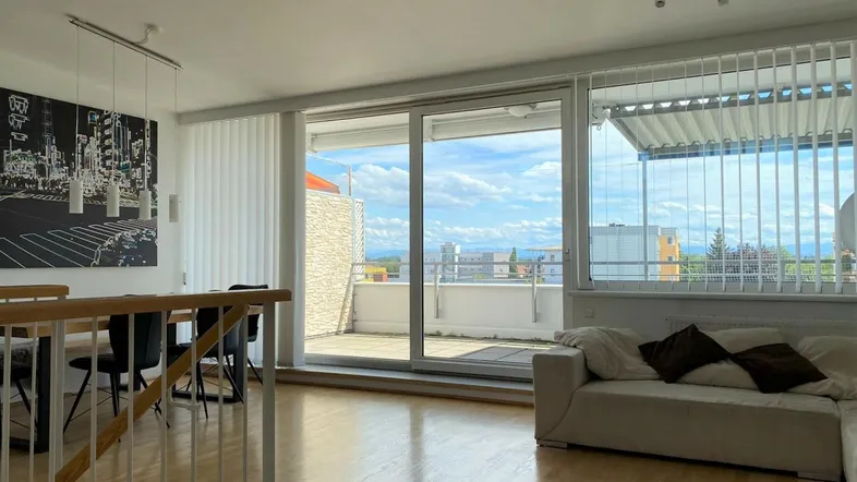 Helles Wohn- und Esszimmer mit Zugang zur Terrasse und weitem Blick über die Umgebung.