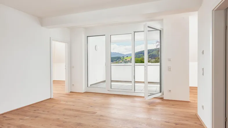 Geräumiges Wohnzimmer mit Holzboden und Zugang zu einem Balkon mit schöner Aussicht.