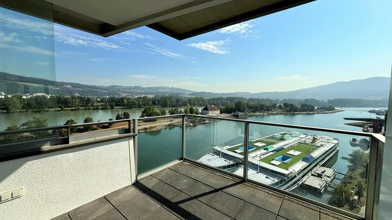 Geräumiger Balkon mit Glasbrüstung und weitem Blick auf den Fluss und die umliegende Landschaft.