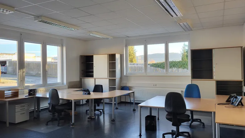 Geräumiges und helles Büro mit mehreren Arbeitsplätzen, großen Fenstern und Blick ins Grüne.