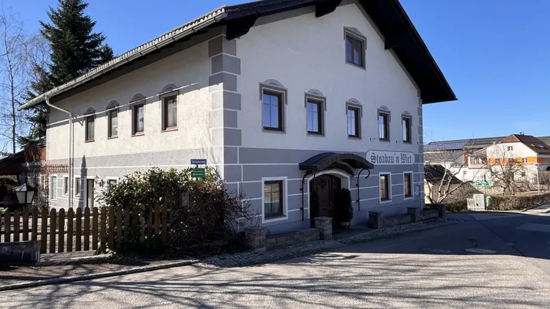 Traditionelles Gebäude mit heller Fassade und grauen Akzenten an einer Straßenecke.