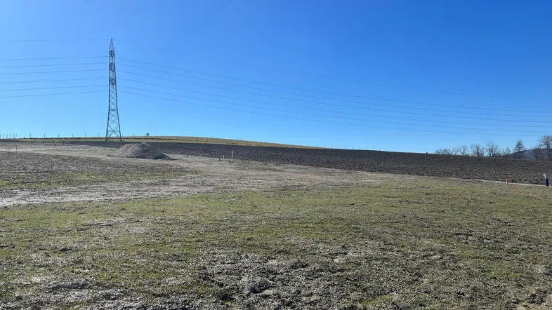 Weitläufiges Grundstück mit leichter Hanglage und Blick auf eine Stromleitung in der Ferne.