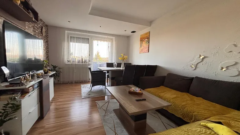 Geräumiger Wohn-Essbereich mit bequemer Couch, Esstisch und hellem Laminatboden.