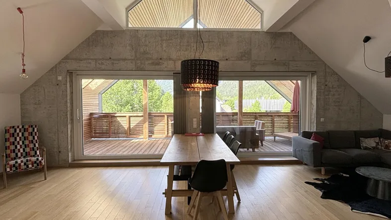 Helles Wohn- und Esszimmer mit Holzboden, Betonelementen und Zugang zur Terrasse.