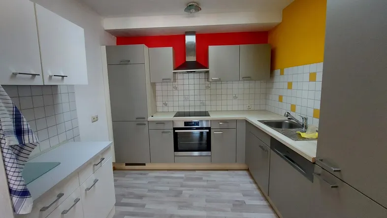 Funktionale Küche mit grauen Schränken, integrierten Geräten und farbigen Wänden.