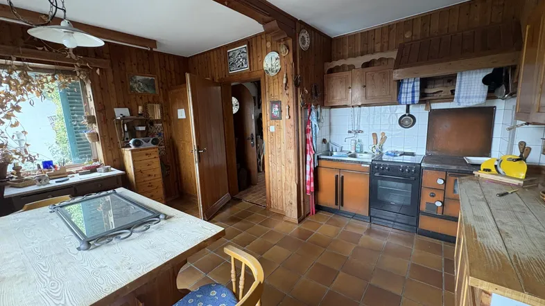 Traditionelle Küche mit Holzvertäfelung, Terrakotta-Fliesenboden und rustikalen Möbeln, bietet eine gemütliche Atmosphäre.