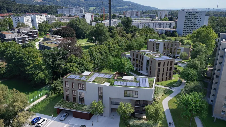 Luftaufnahme moderner Wohngebäude mit Gründächern, Solarpaneelen und umgebender Grünfläche.