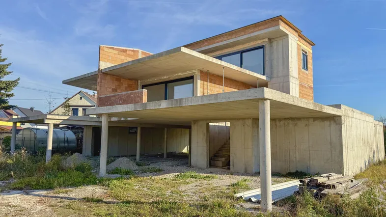 Moderner Neubau im Rohbauzustand mit großen Fensterfronten und massiver Betonkonstruktion.