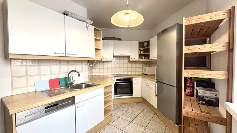 Funktionale Küche mit weißen Schränken, Holz-Arbeitsplatten und Fliesenboden.