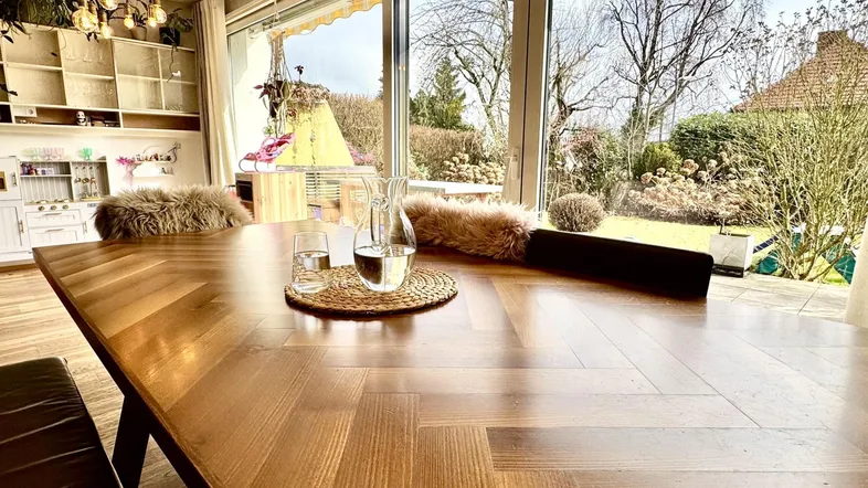 Heller Essbereich mit großem Holztisch, Parkettboden und direktem Zugang zum Garten.