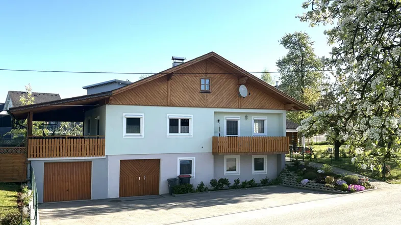Traditionelles Einfamilienhaus mit Holzbalkonen, Satteldach und integrierter Doppelgarage.