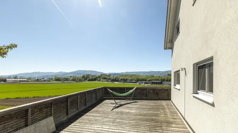 Große Holzterrasse mit Hängematte und weitem Blick über die umliegende Landschaft.