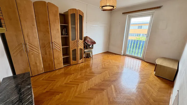 Geräumiges Schlafzimmer mit Holzschränken und Zugang zu einem französischen Balkon.