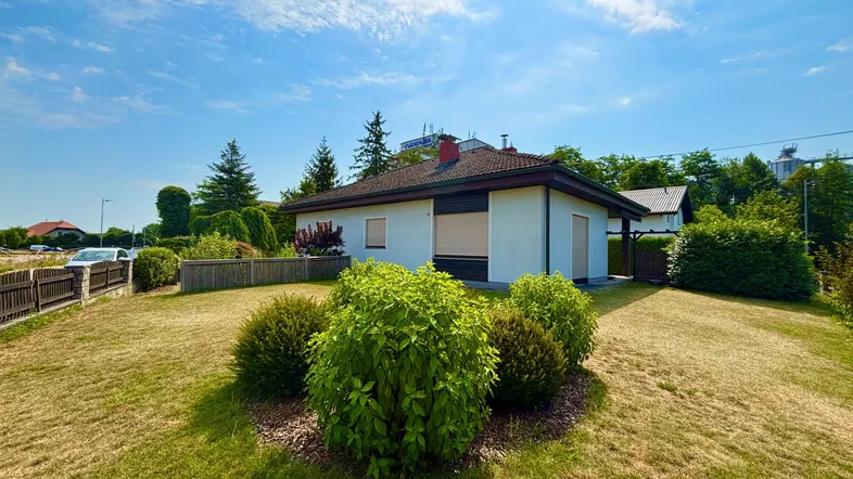 Einfamilienhaus mit gepflegtem Vorgarten und Rasenfläche unter blauem Himmel.