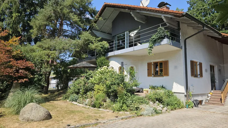 Attraktives Einfamilienhaus mit Balkon, gepflegtem Vorgarten und einer gepflasterten Auffahrt.