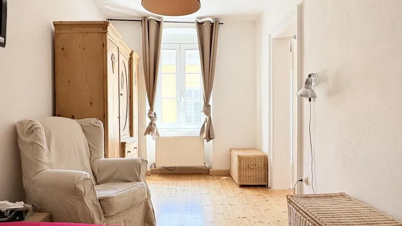 Helles Schlafzimmer mit Holzboden, großem Kleiderschrank und gemütlichem Sessel.