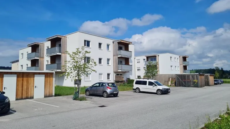 Moderne Mehrfamilienhäuser mit Balkonen und Holzverkleidung unter blauem Himmel.