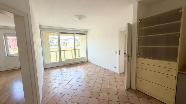 Helles Zimmer mit Fliesenboden und Zugang zu einem Balkon, bietet viel Tageslicht.